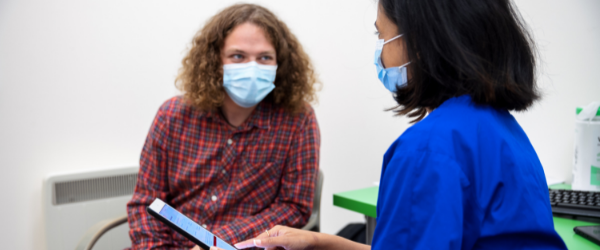 A nurse holding an ipad showing it to a male